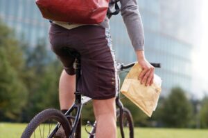Taxifahrer Jobs als Teil mobiler Arbeitswelten: Fahrradkurier mit Sendung unterwegs im Stadtgebiet – Symbolbild fuer flexible Jobs ohne Buero
