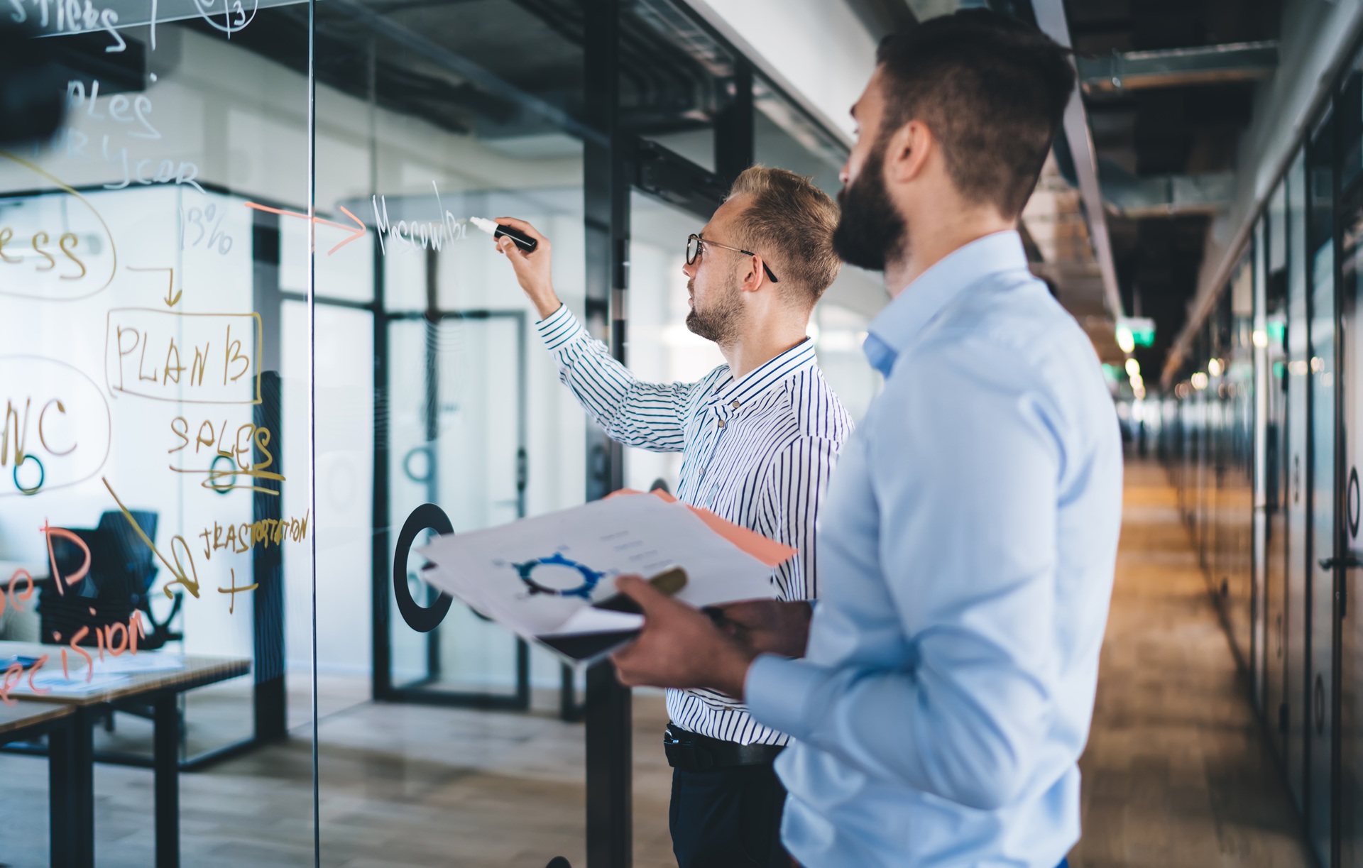 Maenner schreiben Planungen an Glaswand | EmployeeAssistanceProgram