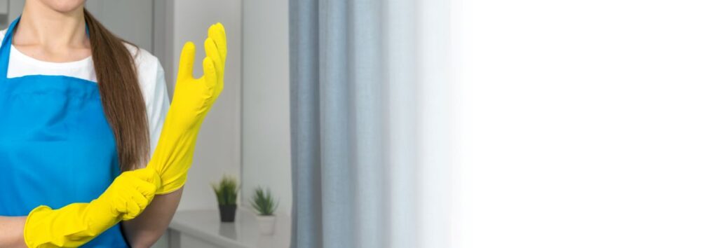 Reinigungskraft zieht gelbe Handschuhe an und bereitet sich auf gruendliche Wohnungsreinigung Berlin vor