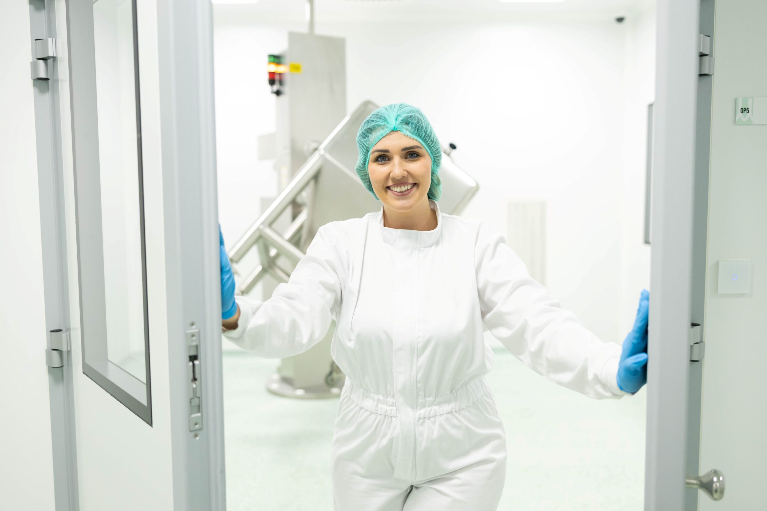 Mitarbeiterin im Reinraum öffnet Türen und symbolisiert Vertrauen bei der Auswahl des richtigen Partners